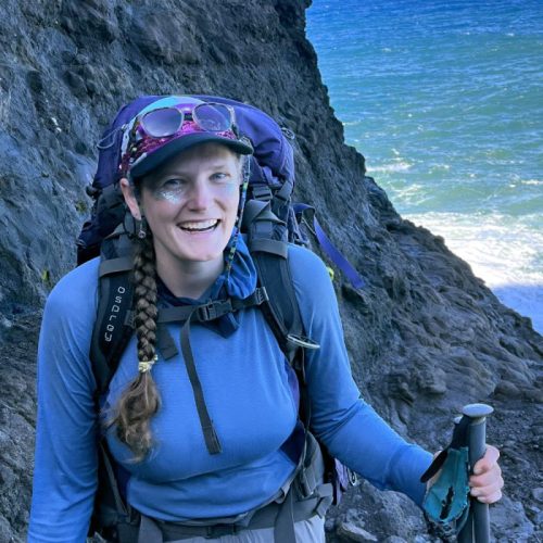 Hannah hiking on rocky seaside.
